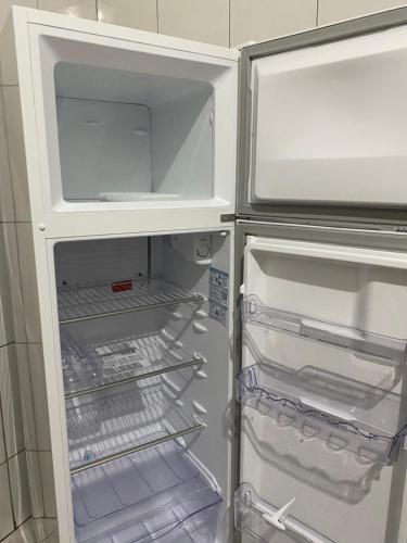 an empty refrigerator with its door open in a kitchen at Apartamento em frente Basílica in Aparecida