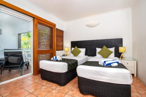 a bedroom with two beds and a balcony at Paradise On The Beach Resort in Palm Cove