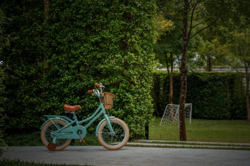 a blue bike parked on a sidewalk next to a bush at Hotel Labaris Khao Yai in Mu Si