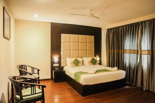 a hotel room with a bed and a chair at J Hotel in Port Blair