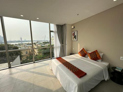 a bedroom with a large bed and large windows at Khe Suites Serviced Apartment - Han River in Danang