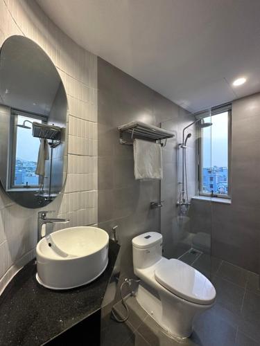 a bathroom with a toilet and a sink and a mirror at Khe Suites Serviced Apartment - Han River in Danang