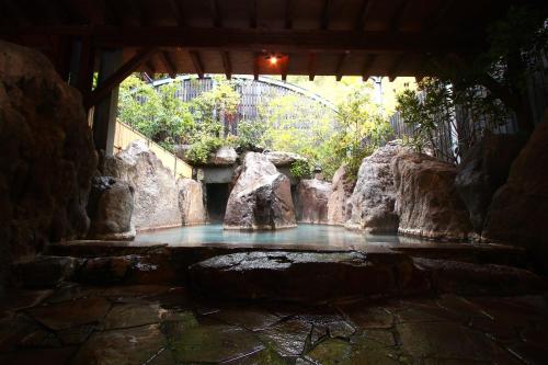 a pool of water with rocks and a bridge at YamakawaZENZO in Oguni