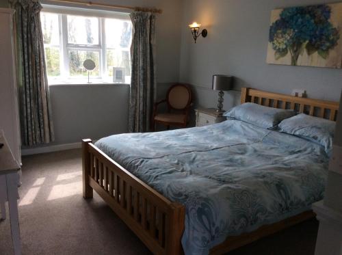 a bedroom with a bed with a blue comforter and a window at The Swan Motel, Gillingham in Beccles
