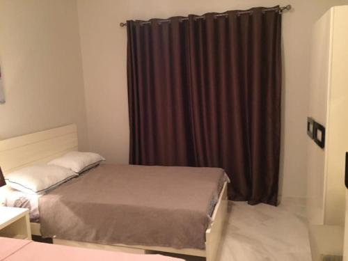Lovely 3-bedroom vacation home -Marassi في الإسكندرية: غرفة نوم بسرير وستارة بنية اللون