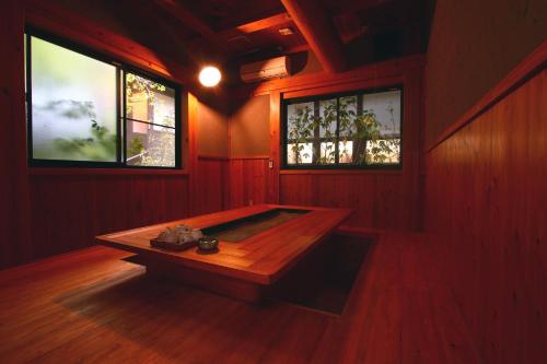 a room with a wooden table and two windows at YamakawaZENZO in Oguni