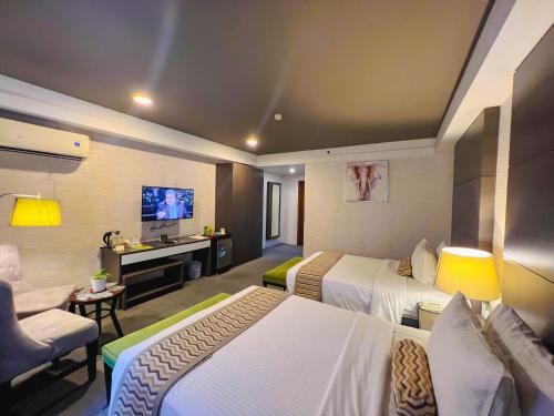 um quarto de hotel com duas camas e uma televisão em 88 Courtyard Hotel em Manilla