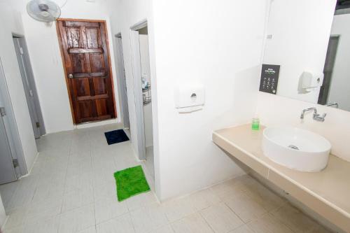 a white bathroom with a sink and a green rug at Mad Monkey Pai in Pai