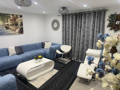 a living room with a blue couch and white chairs at ☆Igloo MagnoliaView Luxe Townhouse + Free Parking☆ in Leeds