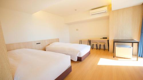 ELE Hotel Kuzuha في هيراكاتا: غرفة فندقية بسريرين وطاولة