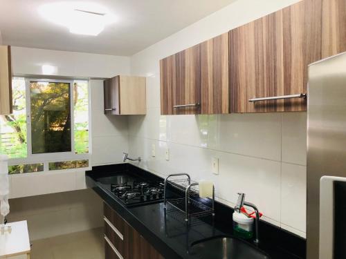 a kitchen with a black counter top and wooden cabinets at Tambaú Home Beira Mar - com varanda in João Pessoa