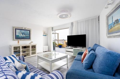 a living room with a blue couch and a tv at 106 Medano Perfect Seaviews By Sunkeyrents in El Médano