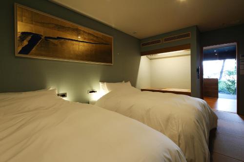 two white beds in a bedroom with a painting on the wall at Monjusou Shourotei in Miyazu