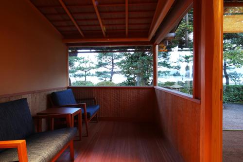 a balcony with two chairs and a window at Monjusou Shourotei in Miyazu