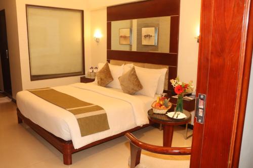 een slaapkamer met een groot bed en een tafel bij Kyriad Hotel Indore by OTHPL in Indore