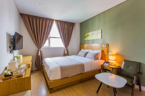 - une chambre avec un lit, une table et une télévision dans l'établissement Lamer Hotel, à Busan