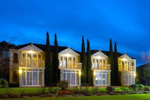 a large house with a row of cypress trees at Best Western Colonial Village Motel in Warrnambool