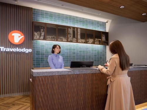 two women standing at a reception counter in a lobby at Travelodge Nagoya Sakae in Nagoya