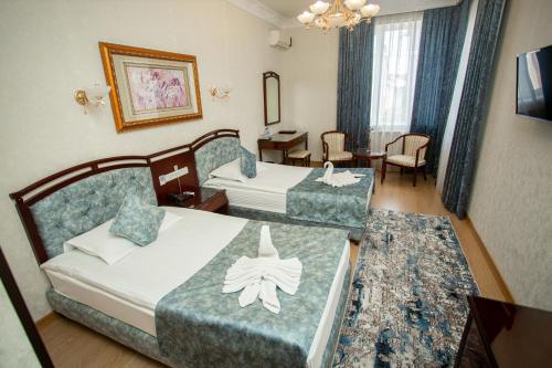 a hotel room with two beds and a table and chairs at Hotel Asia Samarkand in Khodzha-Akhrar