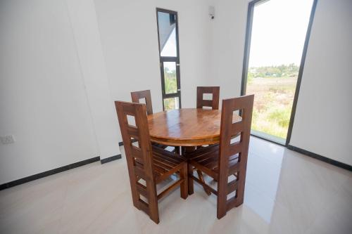 einen Holztisch und Stühle in einem Zimmer mit Fenster in der Unterkunft Ehala Family Rest in Anuradhapura