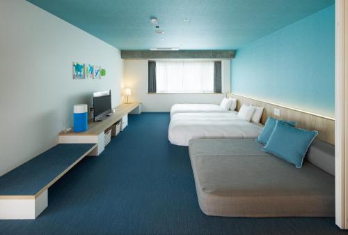 une chambre d'hôtel avec deux lits et un canapé dans l'établissement Hoshino Resorts BEB5 Okinawa Serakaki, à Onna