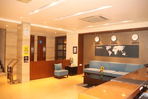 a waiting room with a blue couch and clocks on the wall at Kyriad Hotel Indore by OTHPL in Indore