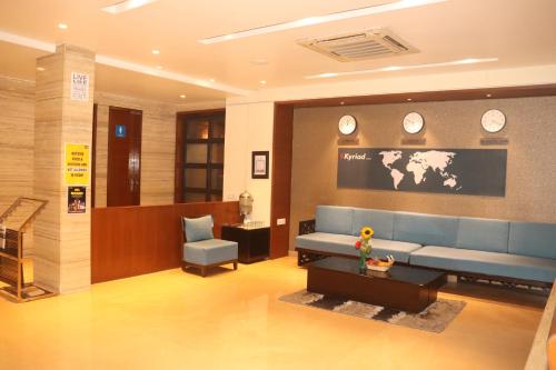 a waiting room with a blue couch and clocks on the wall at Kyriad Hotel Indore by OTHPL in Indore