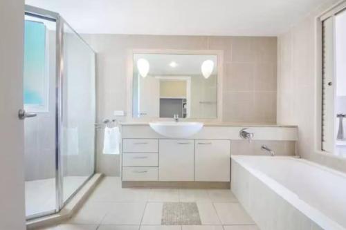 a bathroom with a sink and a tub and a mirror at Palm Springs - Hosted by Burleigh Letting in Gold Coast