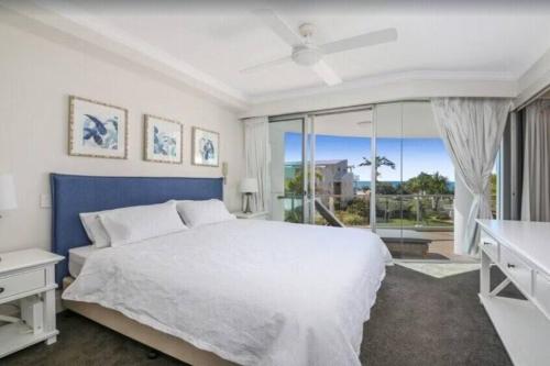 a bedroom with a white bed and a large window at Palm Springs - Hosted by Burleigh Letting in Gold Coast