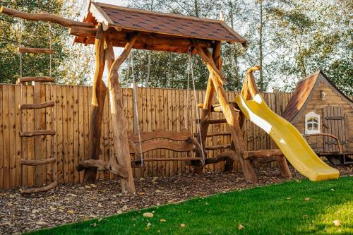 a playground with a swing and a wooden fence at Bespoke Holiday Home With Private Pool And Hot Tub, Sleeps 8 Ref 34073P in Kings Lynn