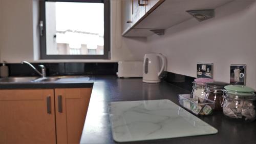 a kitchen with a sink and a counter with jars on it at Albion Street Apartments in Wolverhampton