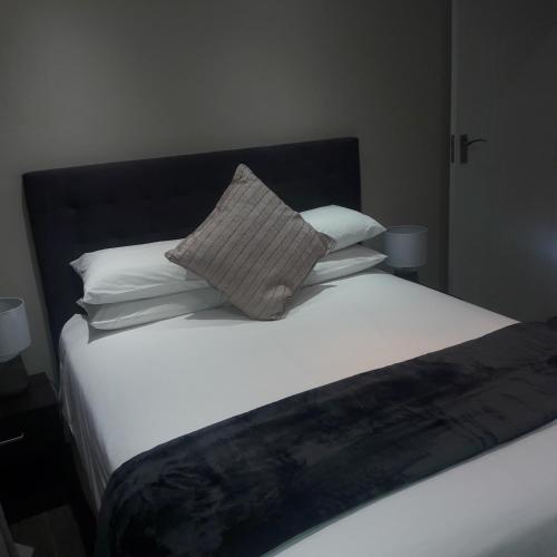 a bed with white sheets and pillows at Whispering Pines Country Estate in Magaliesburg