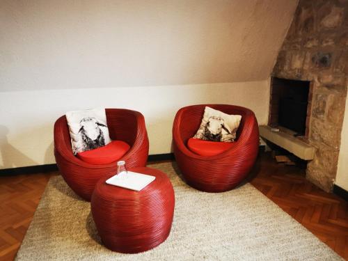 twee rode stoelen in een kamer met een open haard bij les bois de saint Auvent in La Geneytouse