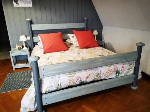 ein Schlafzimmer mit einem Bett mit zwei roten Kissen in der Unterkunft les bois de saint Auvent in La Geneytouse