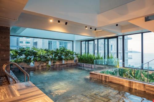 a large indoor swimming pool in a building with windows at The Glomad Danang Hotel in Danang