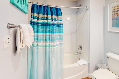 La salle de bains est pourvue d'un rideau de douche bleu à côté d'une baignoire. dans l'établissement Sterling Reef 1205, à Panama City Beach