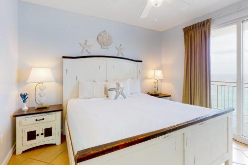 - une chambre avec un grand lit blanc et un balcon dans l'établissement Sterling Reef 1205, à Panama City Beach