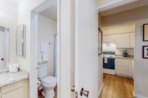 a white bathroom with a toilet and a kitchen at The Heart of Mission Valley in San Diego