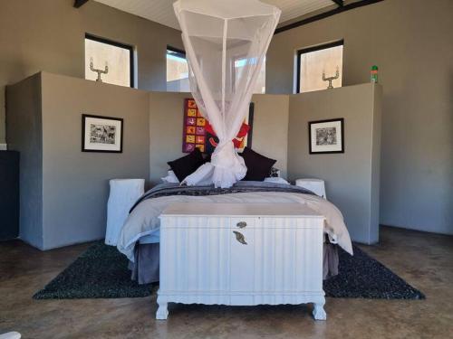 um quarto com uma cama de dossel branca em Hackberry House Black Thorn Cottage, Off Grid em Khemsbok