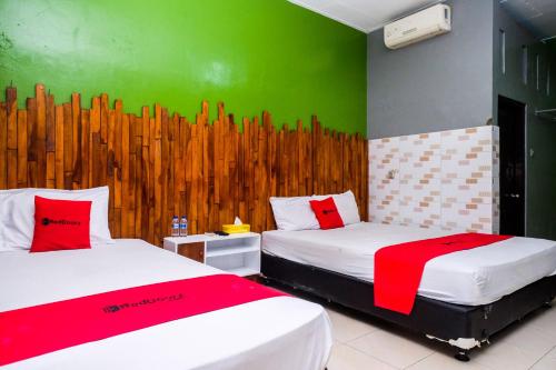 a room with two beds and a green wall at RedDoorz Syariah @ Colomadu 2 in Solo