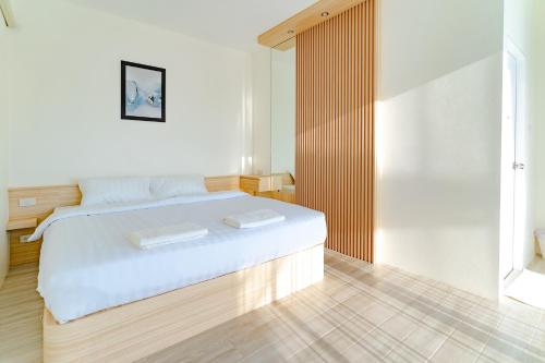 1 dormitorio con 1 cama blanca y 2 toallas en Villa Paramount 2, en Nakhon Nayok