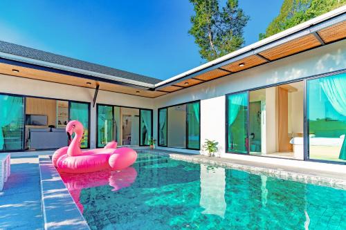un flamenco rosa inflable en una piscina junto a una casa en Villa Paramount 2, en Nakhon Nayok