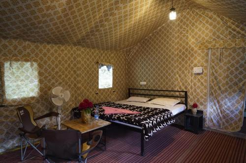 a bedroom with a bed and a table in a room at Forest Acres Camps in Mukteswar