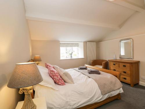 a bedroom with a bed with a lamp and a window at Bower Coach House in Martock