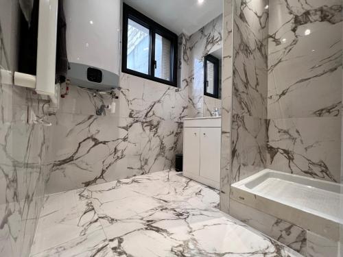 baño con paredes de mármol, lavabo y bañera en SENS - Appartement Proche Gare et Centre ville, en Sens