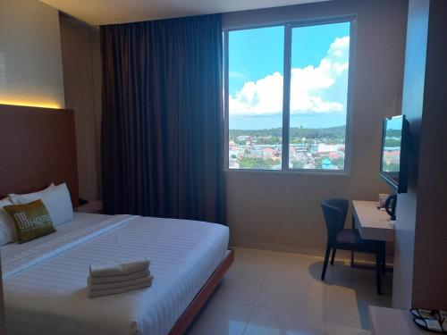 a hotel room with a bed and a desk and a window at OS Hotel Airport Batam in Batam Center