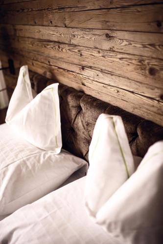 a bed with white pillows and a wooden wall at Hotel Gotthard in Lech am Arlberg