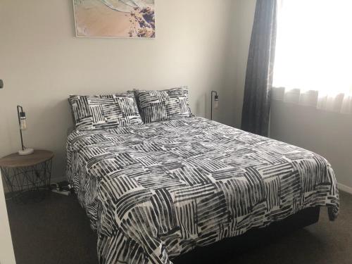 a bedroom with a black and white bed with pillows at #5 on Blenheim St in Renwick