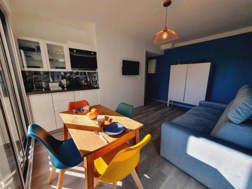 a living room with a table and a blue couch at Suite élégante Club Centre-ville Wifi Piscine - ROSSIconciergerie - Linge inclus in La Grande Motte