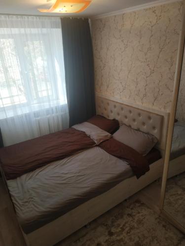 ein kleines Bett in einem Zimmer mit Fenster in der Unterkunft Аренда 2-ух комнатная посуточно in Balqasch